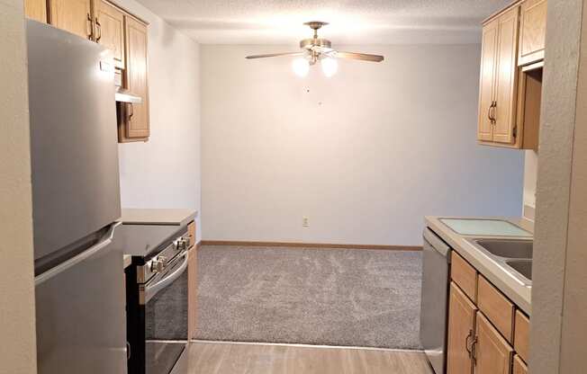 an empty kitchen with stainless steel appliances and a ceiling fan