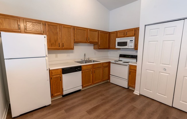 an empty kitchen with white appliances and wooden cabinets