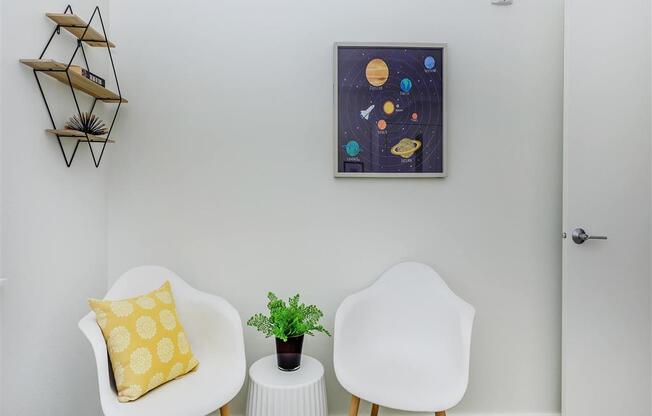 a living room with two white chairs and a small table with a plant on top of it at Jefferson Yards, Washington