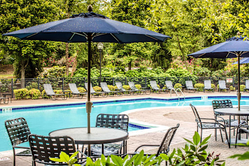 a swimming pool with tables and chairs and umbrellas at Merion Milford Apartment Homes, Milford, 06460