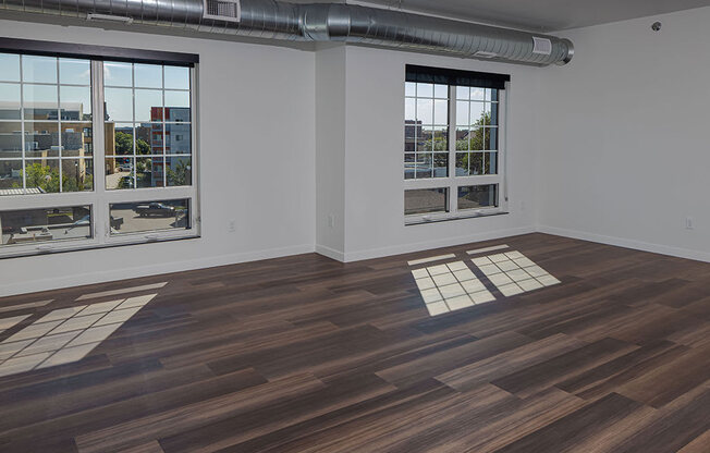 an empty room with hardwood floors and large windows at The Landing at 1001 NP, Fargo, ND 58102