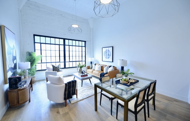 a living room and dining room with white walls and wooden floors