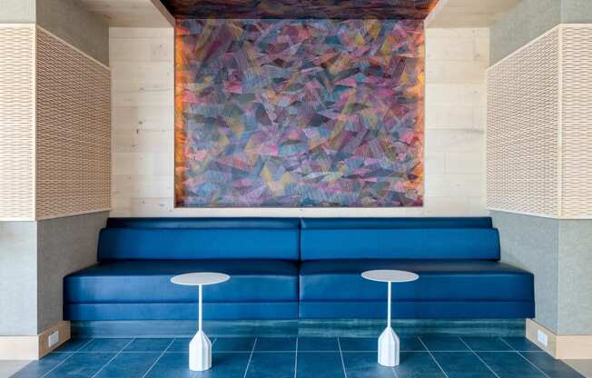 a lobby with blue couches and a painting on the wall