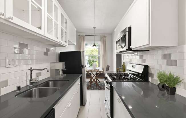 a kitchen with white cabinets and black countertops at Del Mor Apartments, Los Angeles, CA
