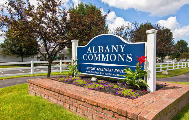 the sign commons in front of a brick retaining wall with flowers
