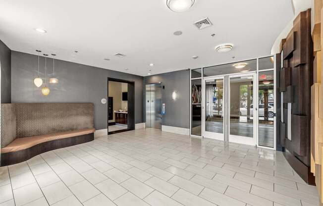 A spacious lobby with a bench and glass doors.