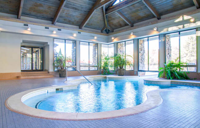 a large indoor swimming pool with glass doors and a wood ceiling