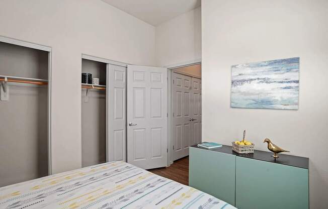 A room with a bed, a cabinet, and a painting on the wall.