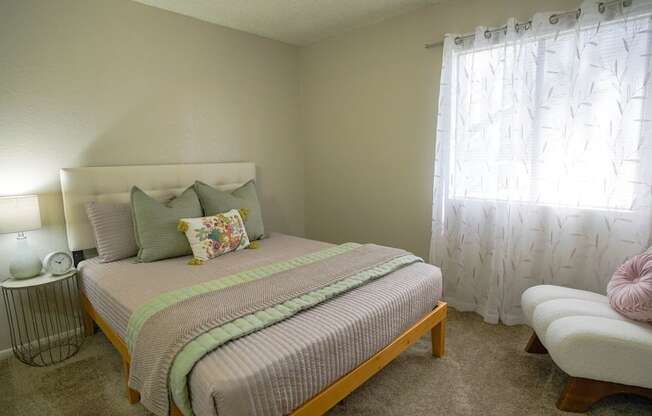 A bedroom with a bed, a chair, and a lamp.