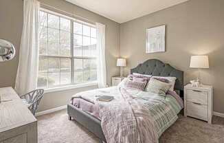 A bedroom with a bed, nightstand, and chair.