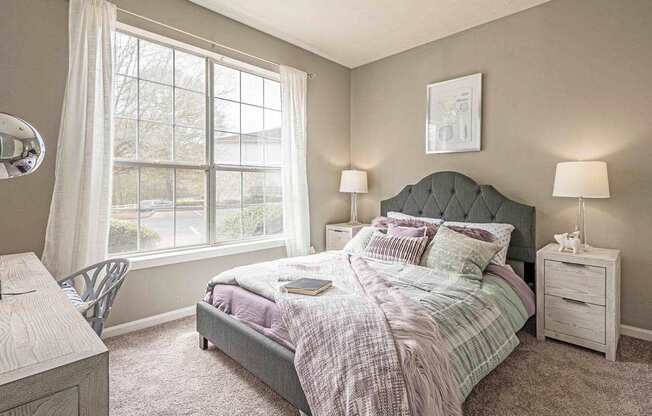 A bedroom with a bed, nightstand, and chair.