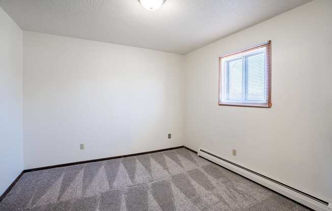 A room with a window and a carpeted floor. West Fargo, ND Parkwest Gardens