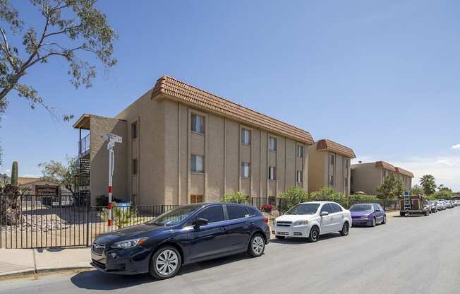 A blue car is parked in front of a building with a red roof.