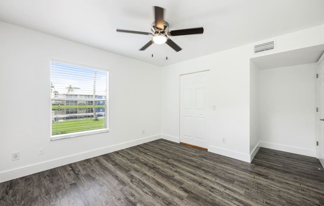 an empty living room with a ceiling fan and a window