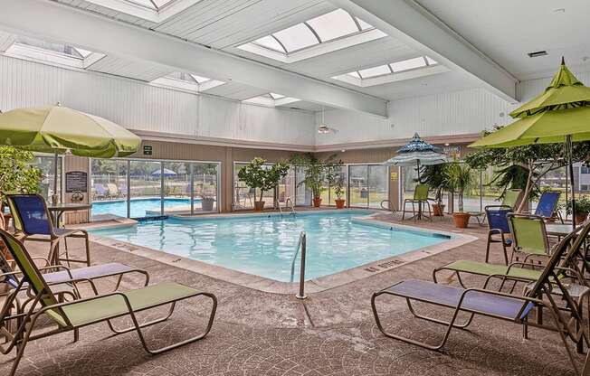 A large indoor swimming pool with sun loungers and umbrellas.