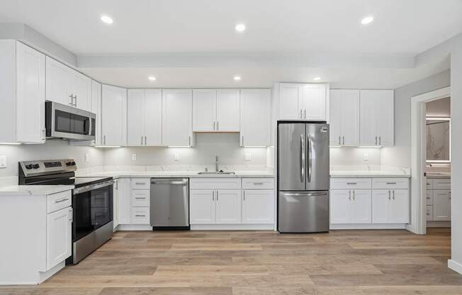 A modern kitchen with white cabinets and stainless steel appliances.