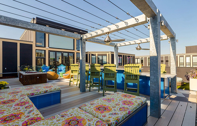 a deck with a pergola and a dining area with blue and yellow chairs at Ann Arbor City Club, Ann Arbor, MI