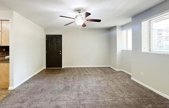 A room with a ceiling fan and carpeted floor.