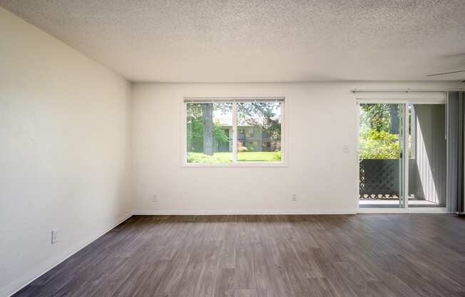 an empty living room with wood floors and a window