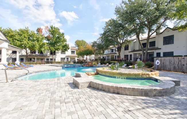 a swimming pool with a jacuzzi and a resort style pool with trees
