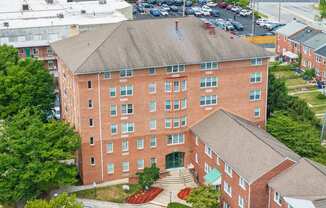 an aerial view of a brick building with trees and a parking lot