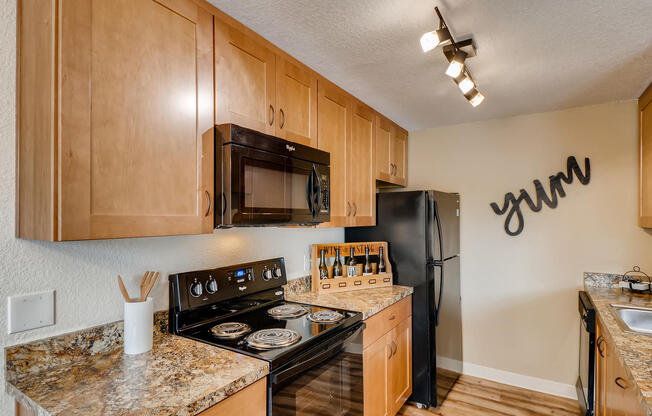 Happy Valley OR Apartments for Rent - Sunnyside Village - Kitchen with Black Appliances, Wood Cabinets, and Granite Countertops