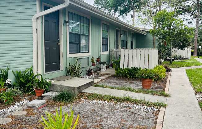 a small blue house with a sidewalk in front of it