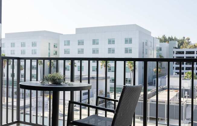 A balcony with a table and chairs overlooking a cityscape.