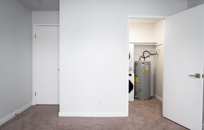 a room with a white wall and a closet and a water heater