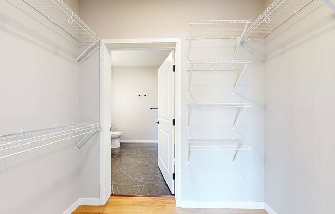a walk in closet with two white closets and a toilet