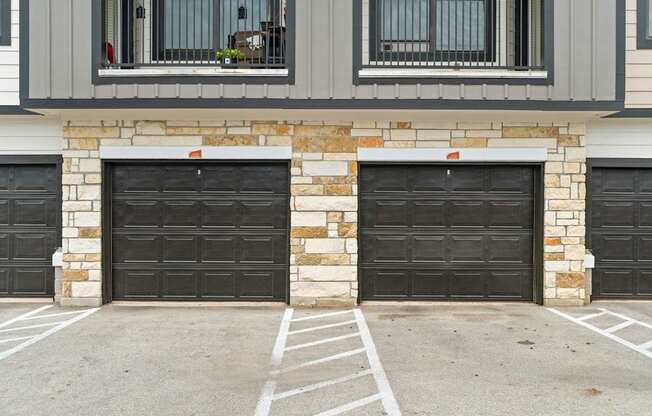 A house with two black garage doors and a stone pillar in the middle.