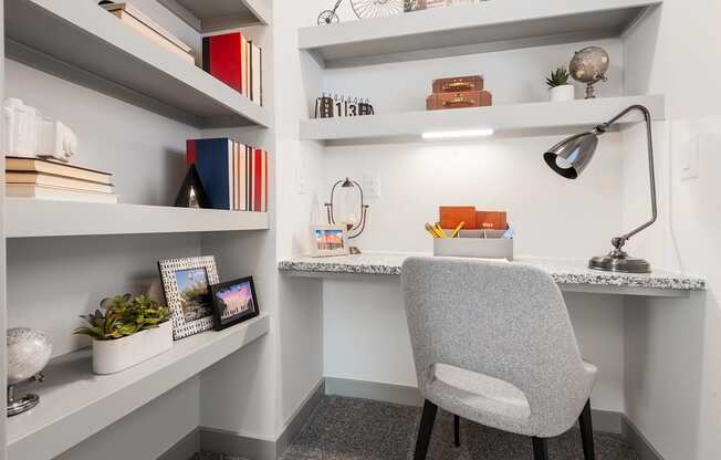 a desk with a chair and shelves in a small room