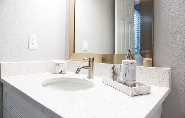A bathroom sink with a marble soap dish holder.