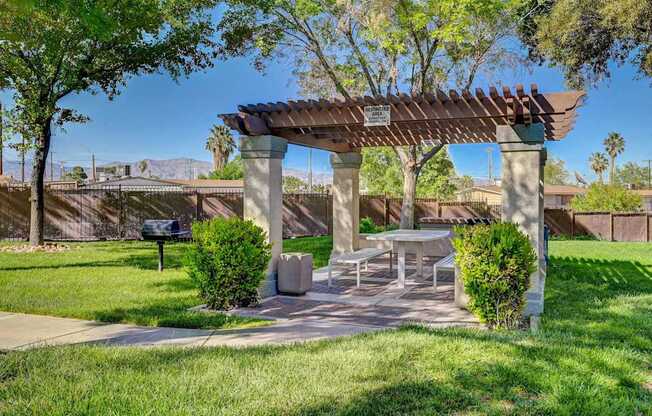 A park with a picnic table and a shaded area under a pergola.