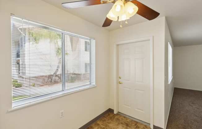 a bedroom with a large window and a ceiling fan