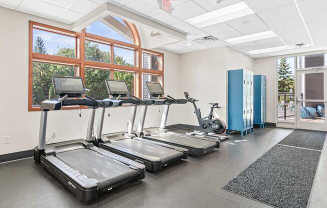 four treadmills in a gym with windows and exercise equipment