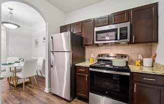 A kitchen with brown cabinets and a stainless steel refrigerator.