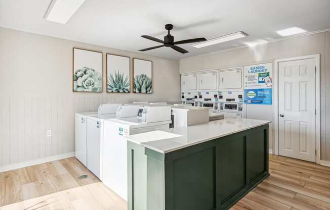 a laundry room with white cabinets and a green island with white appliances