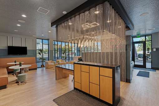 a lobby with a reception desk and chairs and a large glass wall with the name at SevenO2 Main Apartments, Salt Lake City, 84101