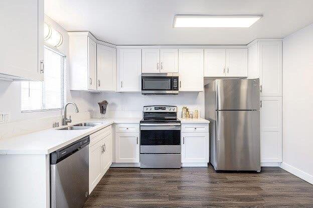A kitchen with white cabinets and a stainless steel refrigerator.