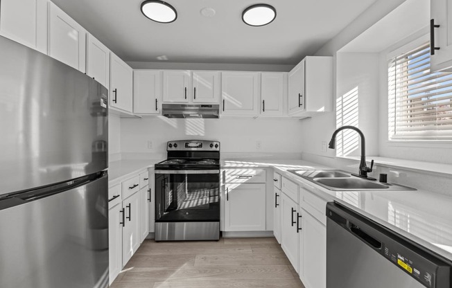 an empty kitchen with white cabinets and stainless steel appliances