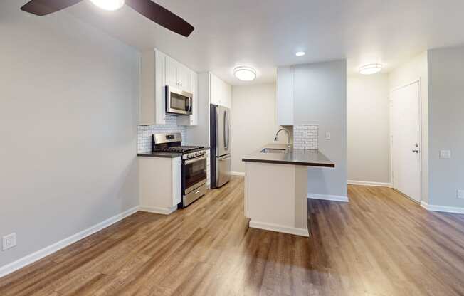 a kitchen with an island and stainless steel appliances and a hard wood floor