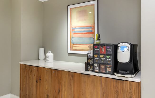 a kitchen counter with a coffee maker and a painting on the wall
