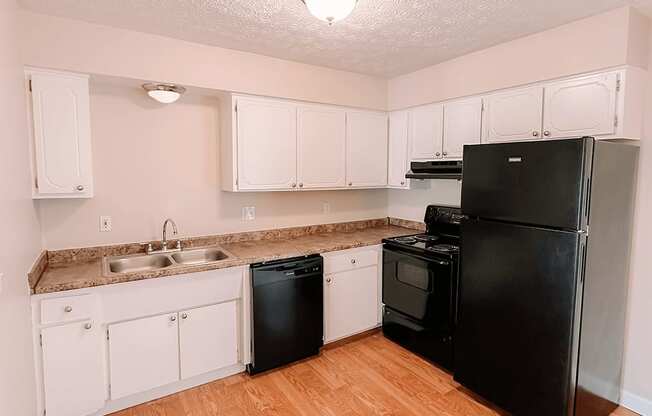 an empty kitchen with black appliances and white cabinets