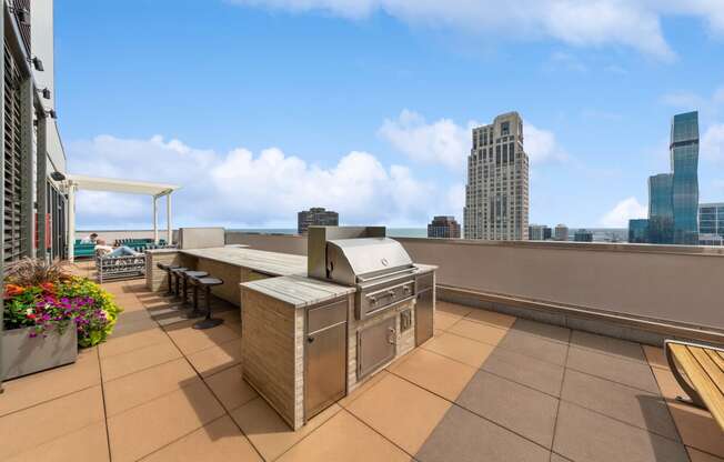 an outdoor barbecue area on the roof of a building with a city skyline in the background