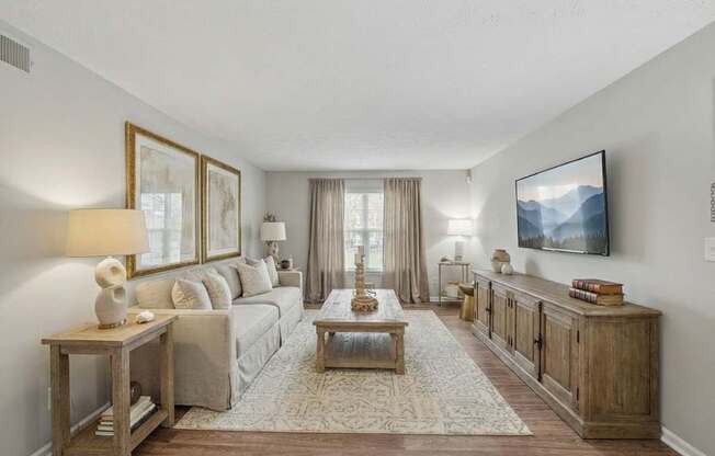 A living room with a couch, a coffee table, and a TV mounted on the wall.
