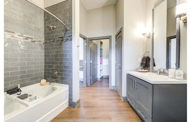 A bathroom with a white sink and a grey tiled wall.