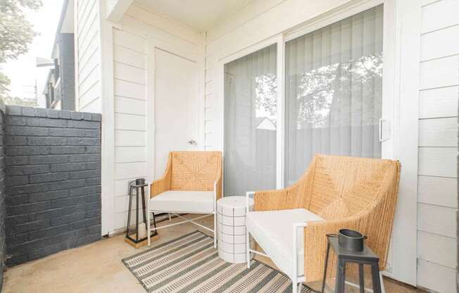 A white chair with a tan cushion is on a porch.