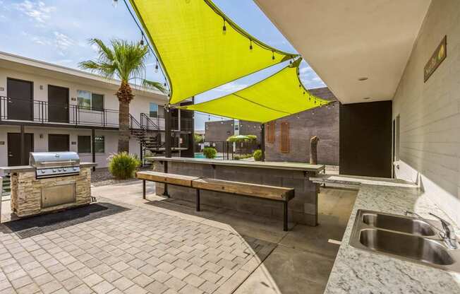 A patio with a yellow canopy and a barbecue grill.