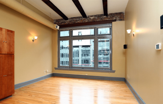 an empty room with a large window and wooden floors